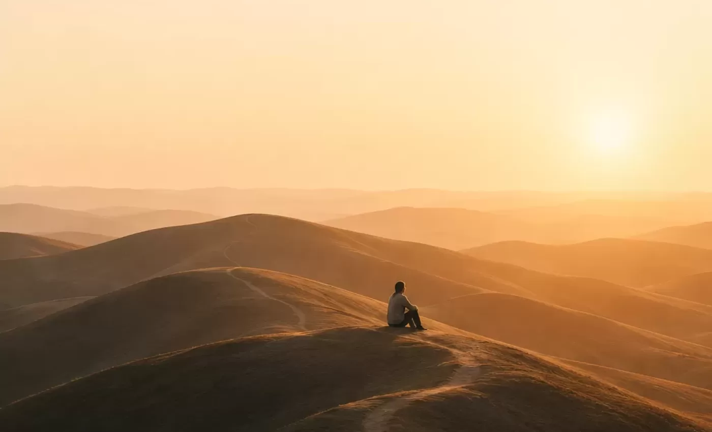 emotional wellness lifelong practice mental health maintenance man sitting on hill in sunset
